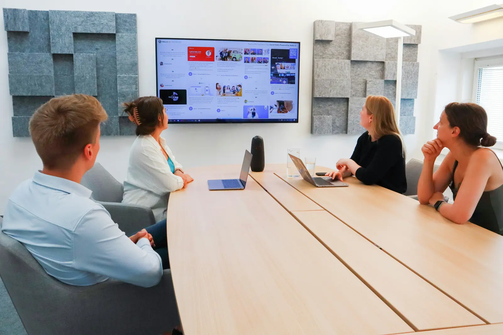 A team reviewing a dashboard on a wall screen in a meeting room